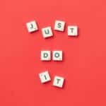 Motivational phrase 'Just Do It' spelled with Scrabble letters on a red background.