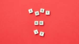 Motivational phrase 'Just Do It' spelled with Scrabble letters on a red background.
