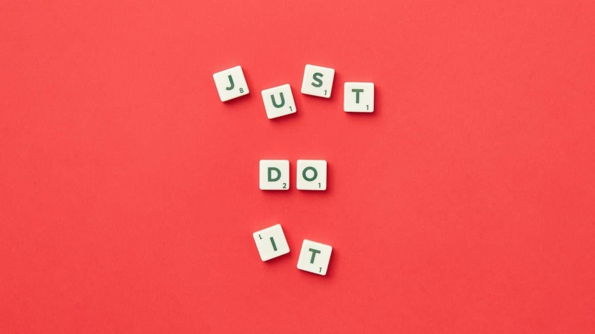 Motivational phrase 'Just Do It' spelled with Scrabble letters on a red background.