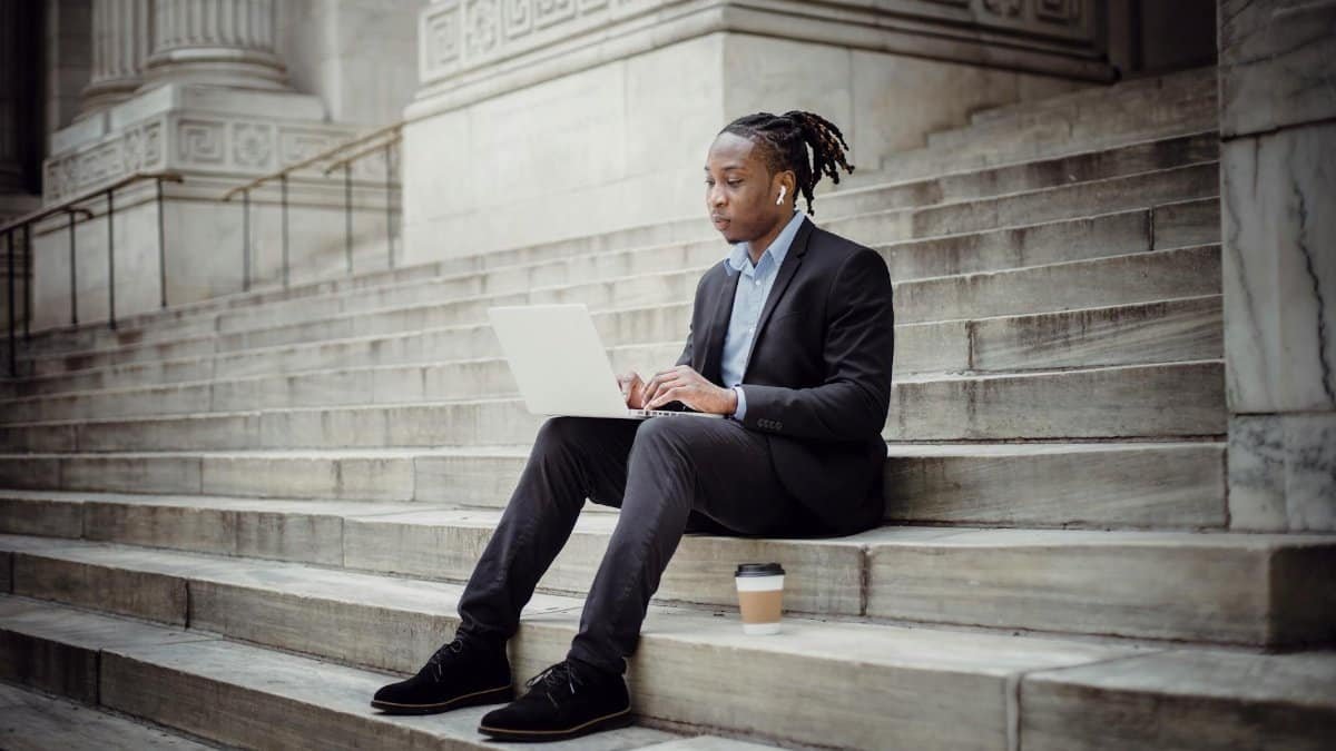 Confident businessman using laptop on urban steps, focused on work.