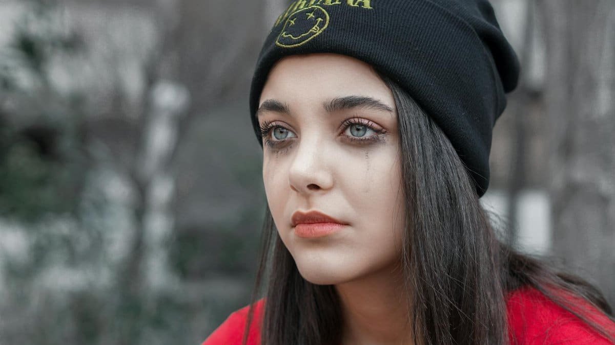 A contemplative young woman in a beanie, captured with a moody tone.