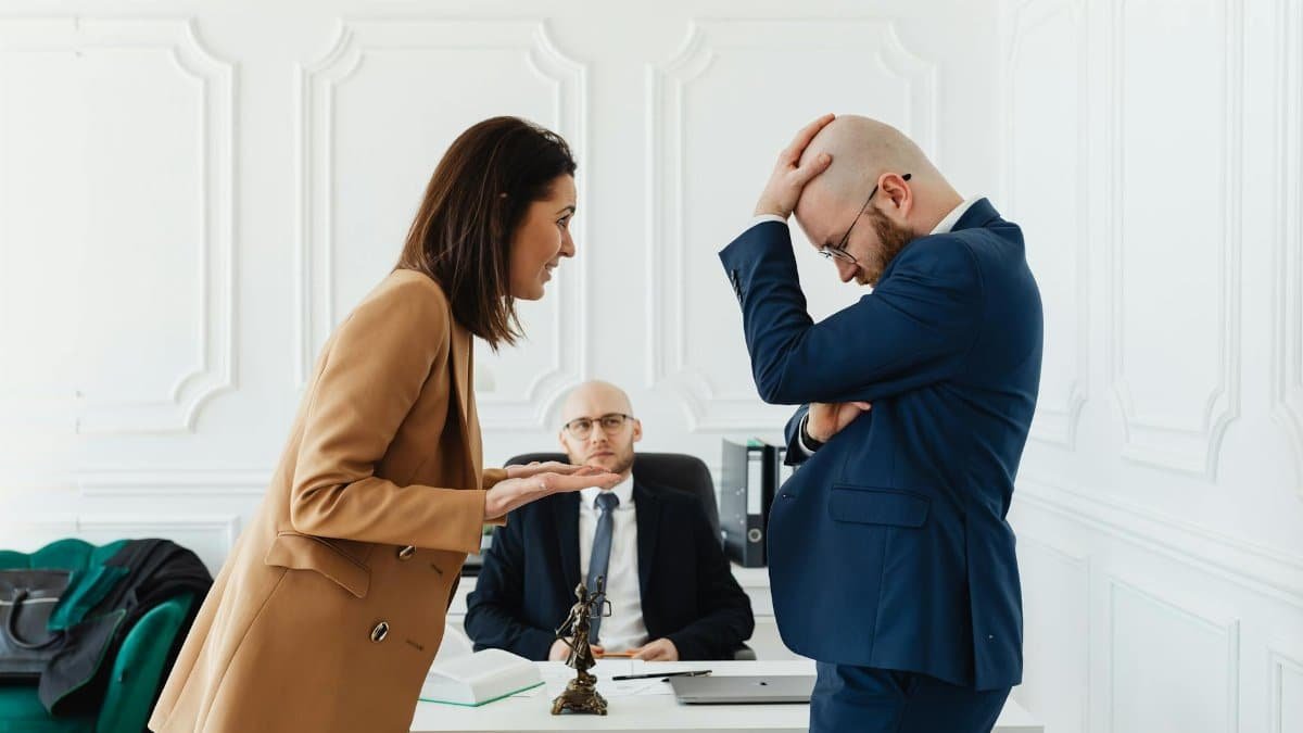 A couple having a heated argument in a law office with their attorney observing.