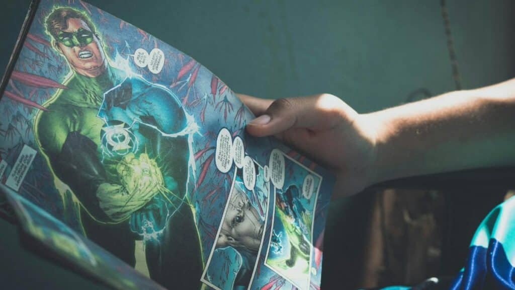 Close-up shot of hands holding a colorful superhero comic book in a sunlit room, depicting leisure reading.