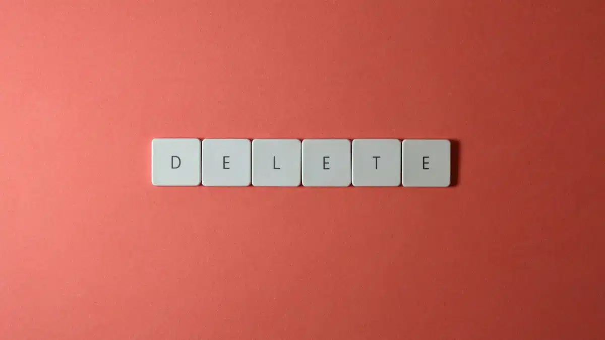 Close-up of keyboard letters spelling 'DELETE' on a coral background, emphasizing digital concepts.