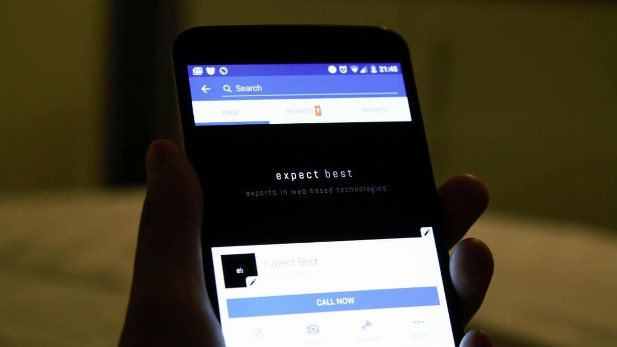 Close-up of a hand holding a smartphone showing a social media application screen.