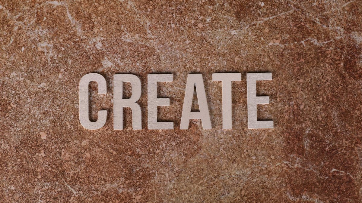 Inspiring CREATE text on a textured brown marble surface, promoting creativity.