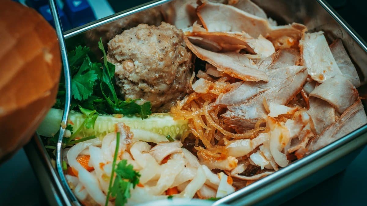 Delicious sliced meat and vegetables packed in a metal lunch box for a flavorful meal.