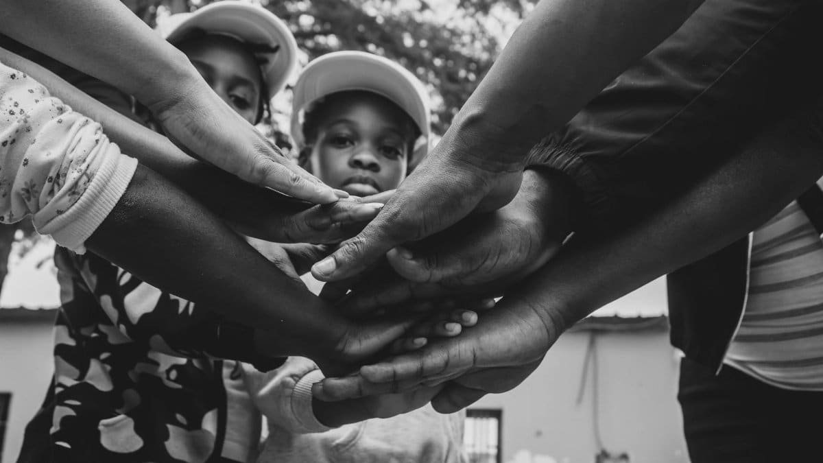 A group of diverse hands joined in solidarity, symbolizing unity and community support in Luanda, Angola.