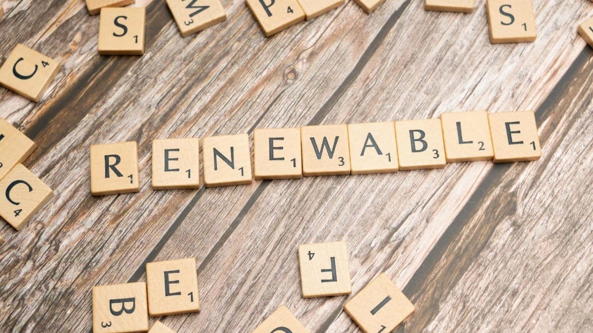 Wooden Scrabble tiles on a wooden table spell 'Renewable' emphasizing sustainability.