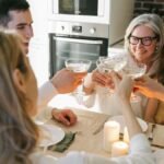 Family gathering with multiple generations toasting together around a dining table with candles.