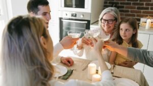 Family gathering with multiple generations toasting together around a dining table with candles.
