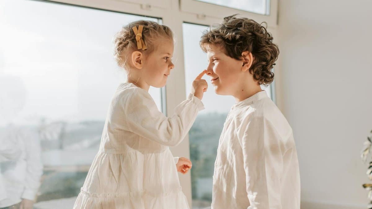 Two happy siblings enjoy a lighthearted moment indoors. Natural lighting enhances the playful mood.