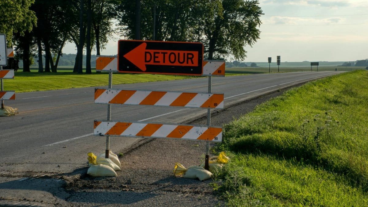 Roadside detour sign with arrow in rural Plainview, MN, under clear skies. Perfect for travel and road maintenance themes.