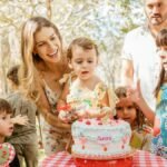 A lively outdoor children's birthday party with cake, family, and friends in a joyful atmosphere.