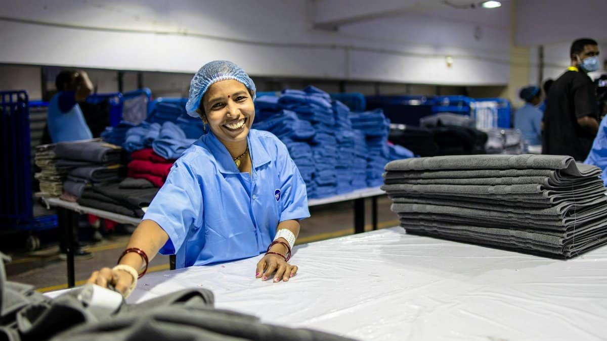 Happy female worker folding textiles in an industrial factory setting.