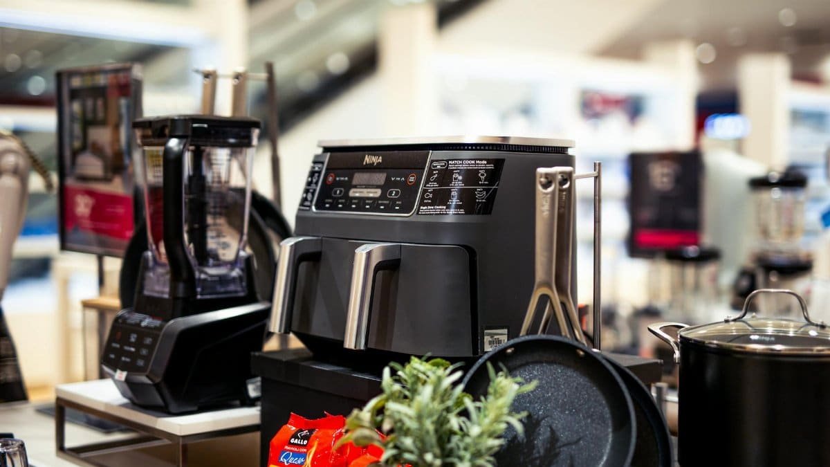 Showcase of modern kitchen appliances in a retail store, featuring blenders and cooking equipment.