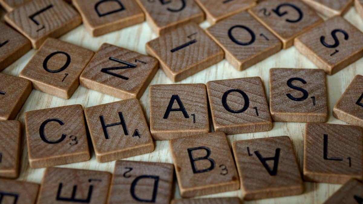 Close-up of scattered wooden letter tiles forming the word 'CHAOS' on a wooden surface.