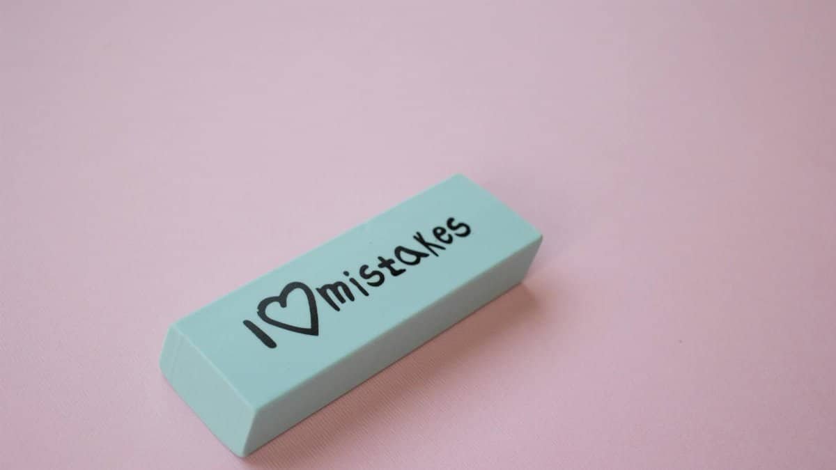 Close-up of a mint green eraser with 'I love mistakes' on a pink background.