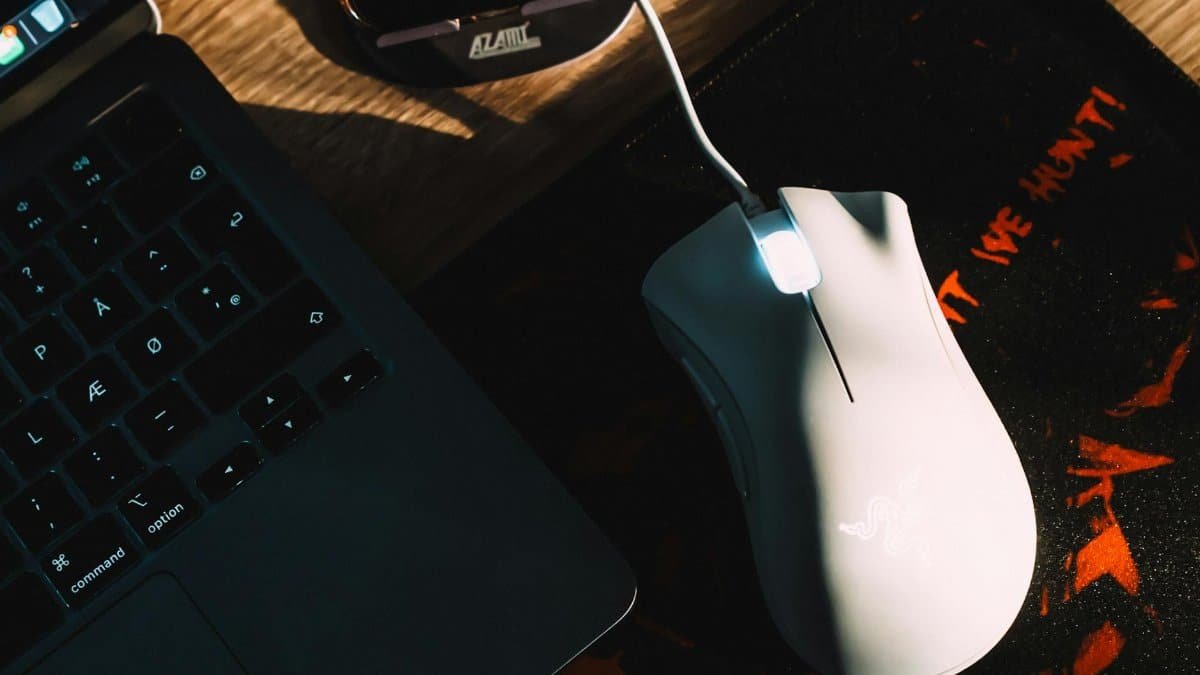 Stylish workspace setup featuring a gaming mouse and laptop with dramatic lighting.