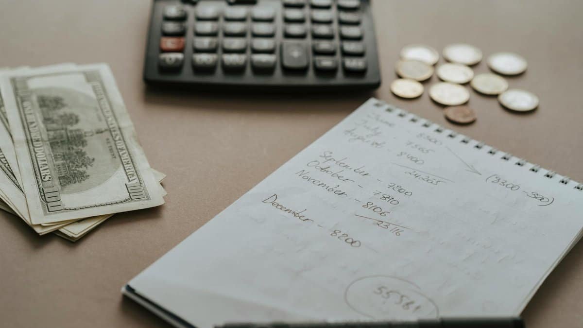 Desk setup showing calculator, cash, coins, and financial notes for budgeting.