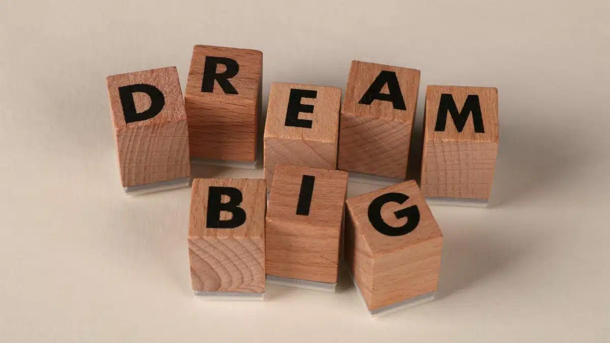 Inspiring arrangement of wooden blocks spelling 'Dream Big' on a neutral beige background.