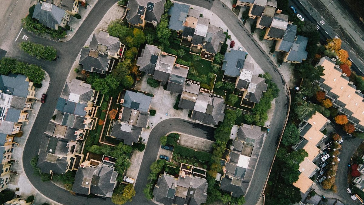 Aerial view of a modern neighborhood with roads and buildings in a lush urban setting.