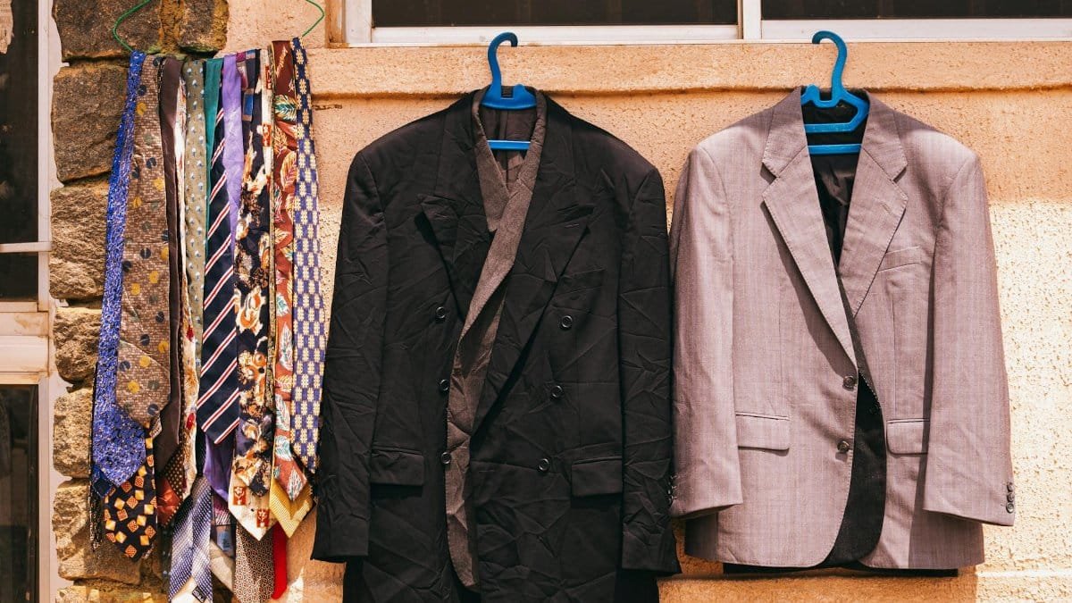 A black and gray suit with colorful ties hanging outdoors on a wall in Jos, Nigeria.