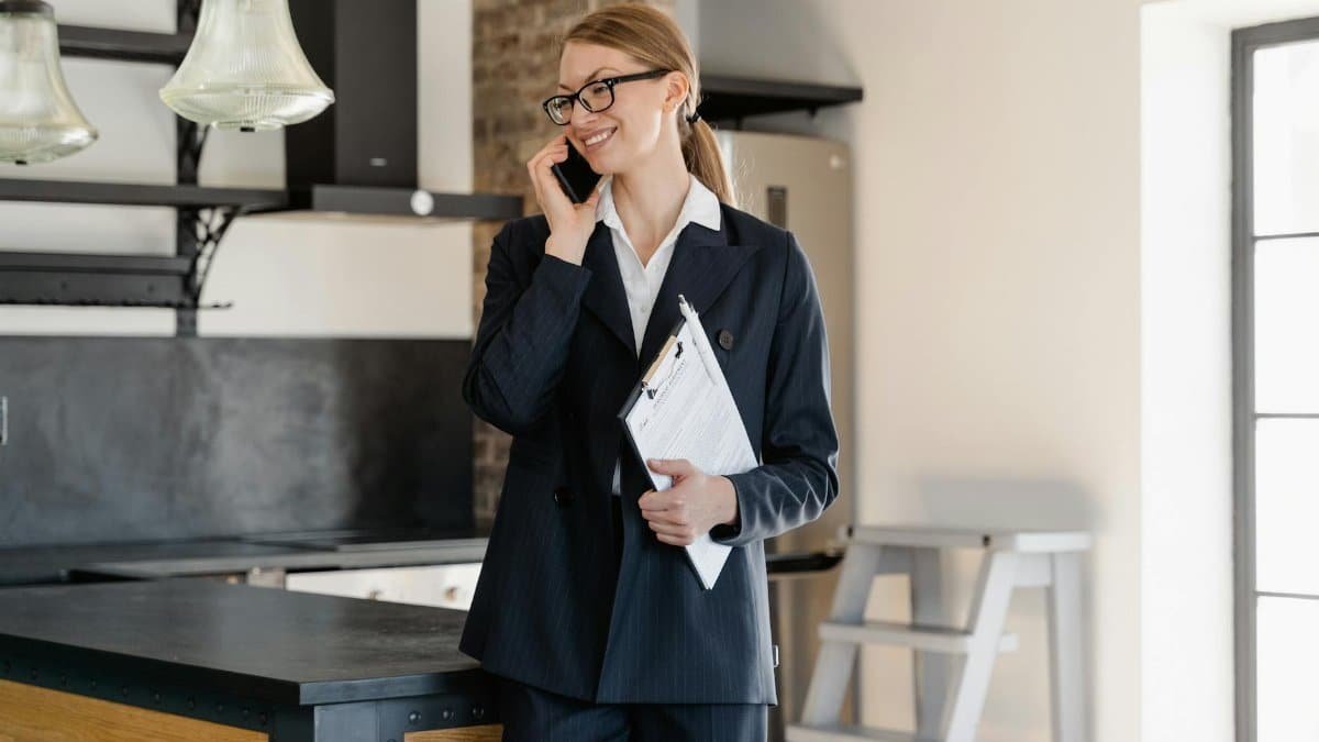 Confident businesswoman in office attire making a call while holding a clipboard in a modern workspace.