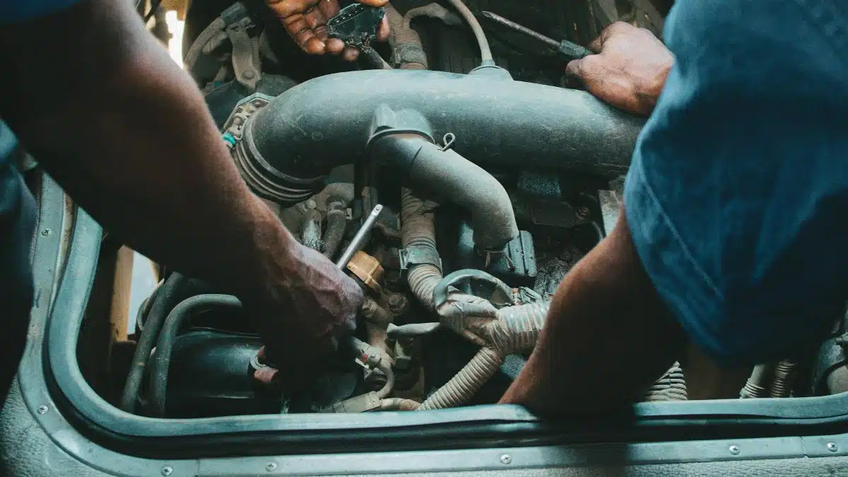 Auto mechanics repairing an engine in a Nigerian workshop. Close-up hands and tools.