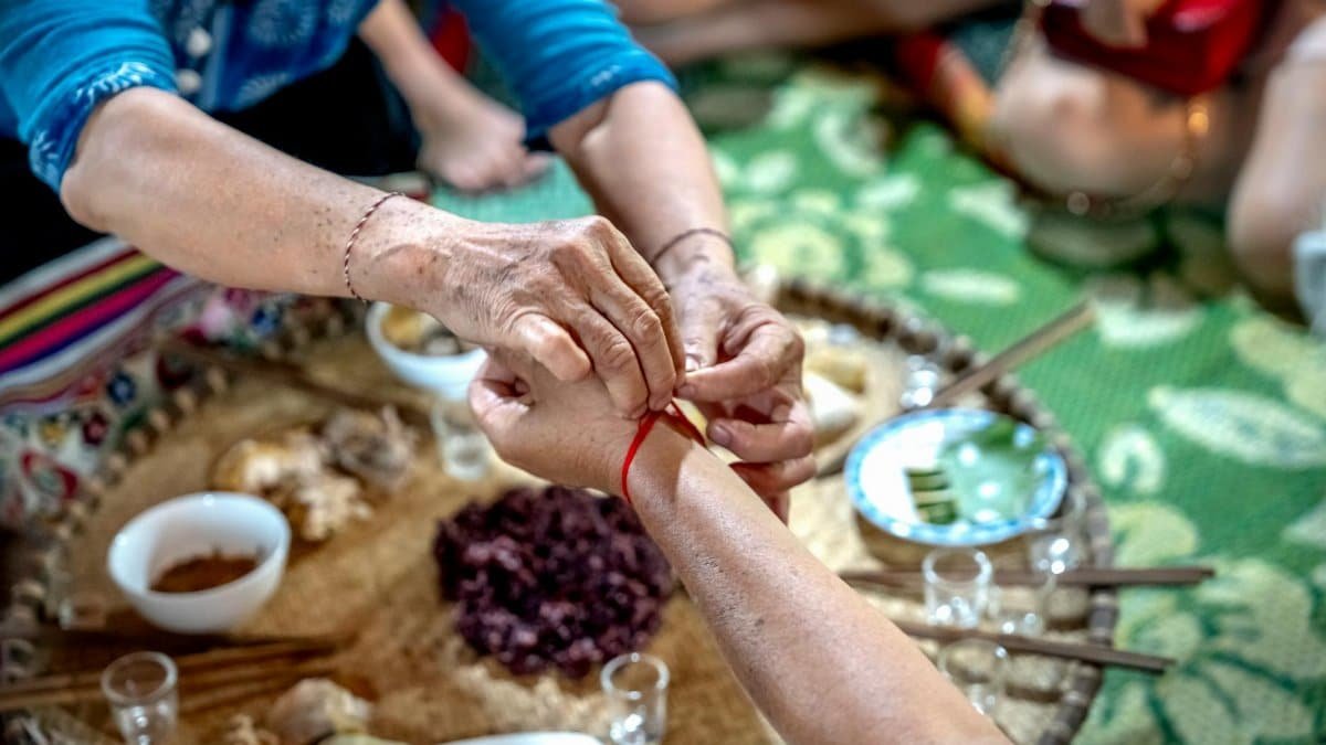 A ritualistic red thread ceremony with adults participating in a traditional setting.