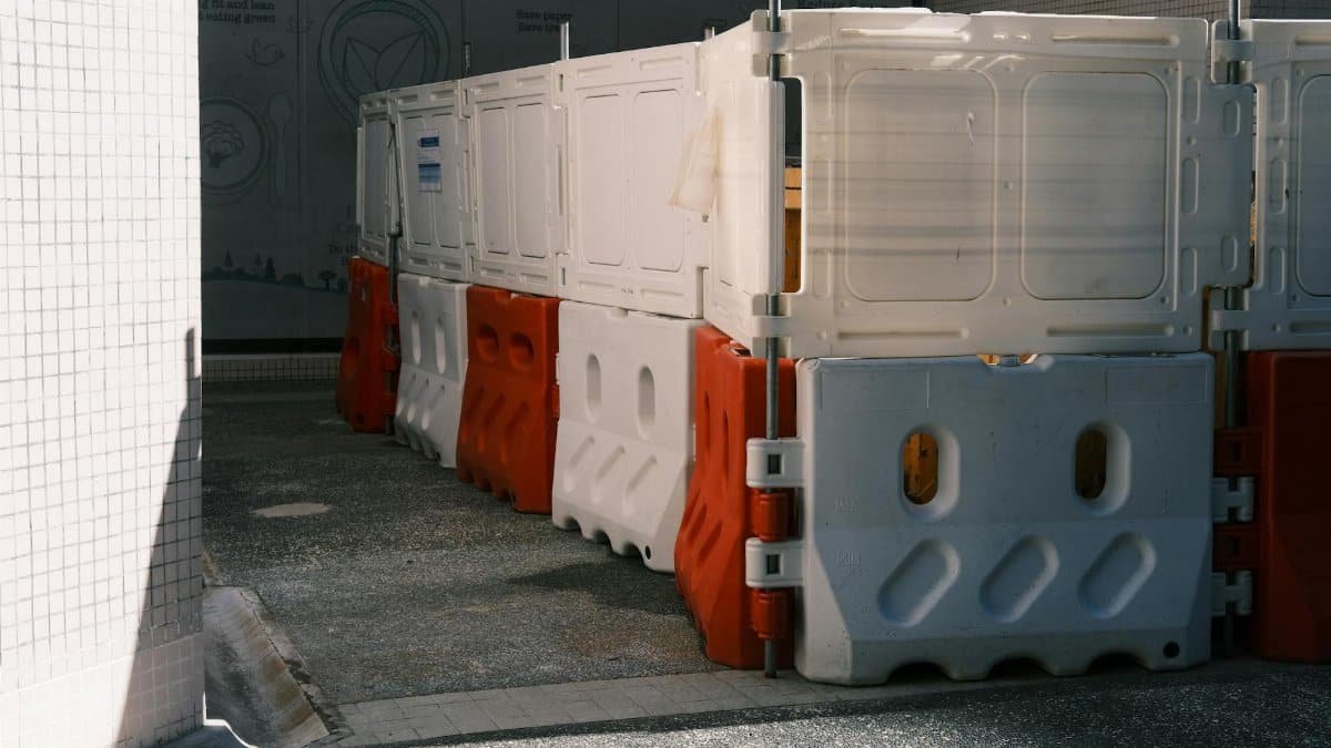 Plastic roadblock barriers with red and white colors in an urban area.
