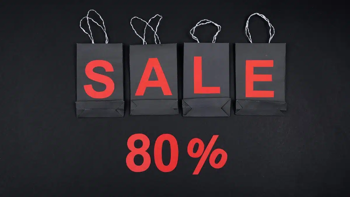 Highlighting a sale with 80% discount using black shopping bags and bold red text.