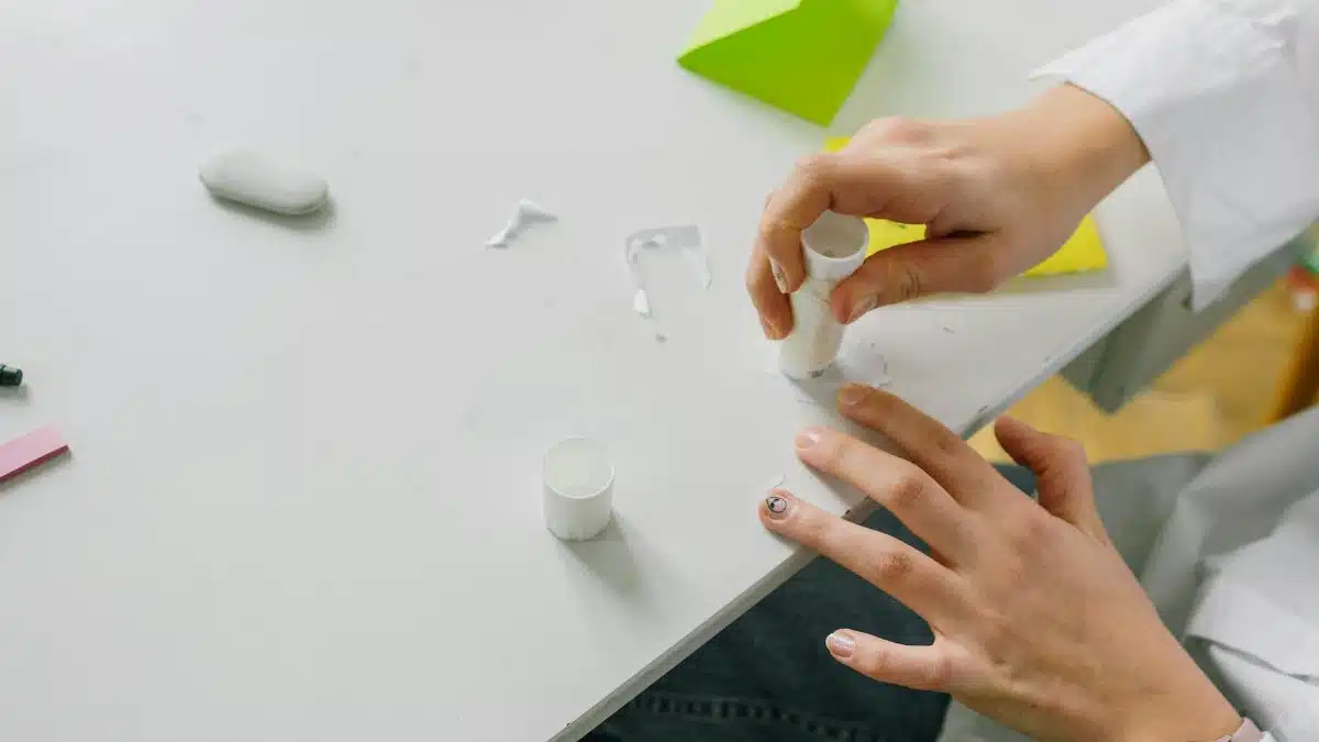 Close-up of hands applying glue stick on paper for a craft project on a desk.