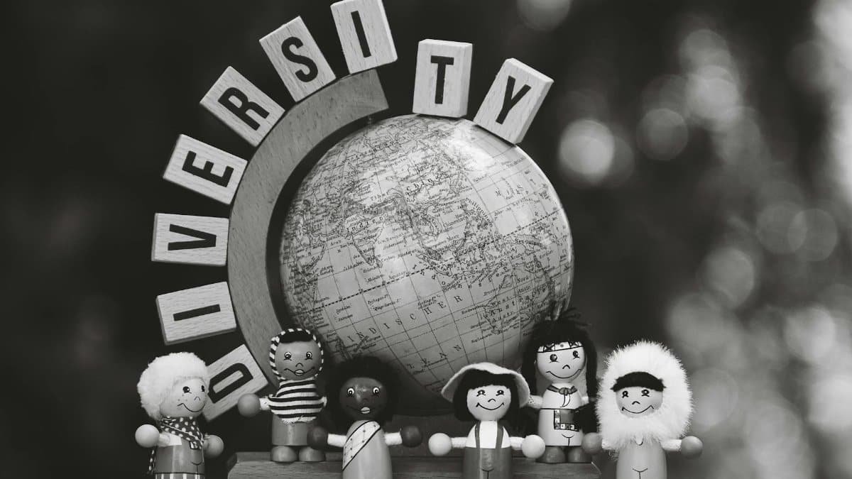 Black and white image of diverse wooden dolls and a globe representing cultural diversity.