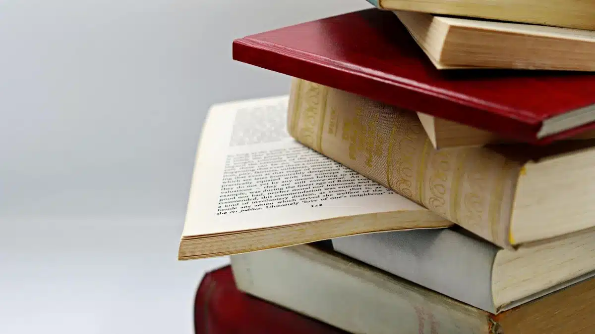 A close-up view of a stack of vintage and modern books with a focus on open pages, offering a sense of knowledge and history.
