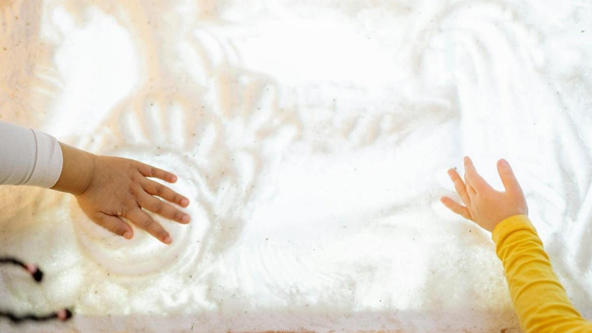 Two children interacting with a textured illuminated surface, engaging sensory play.