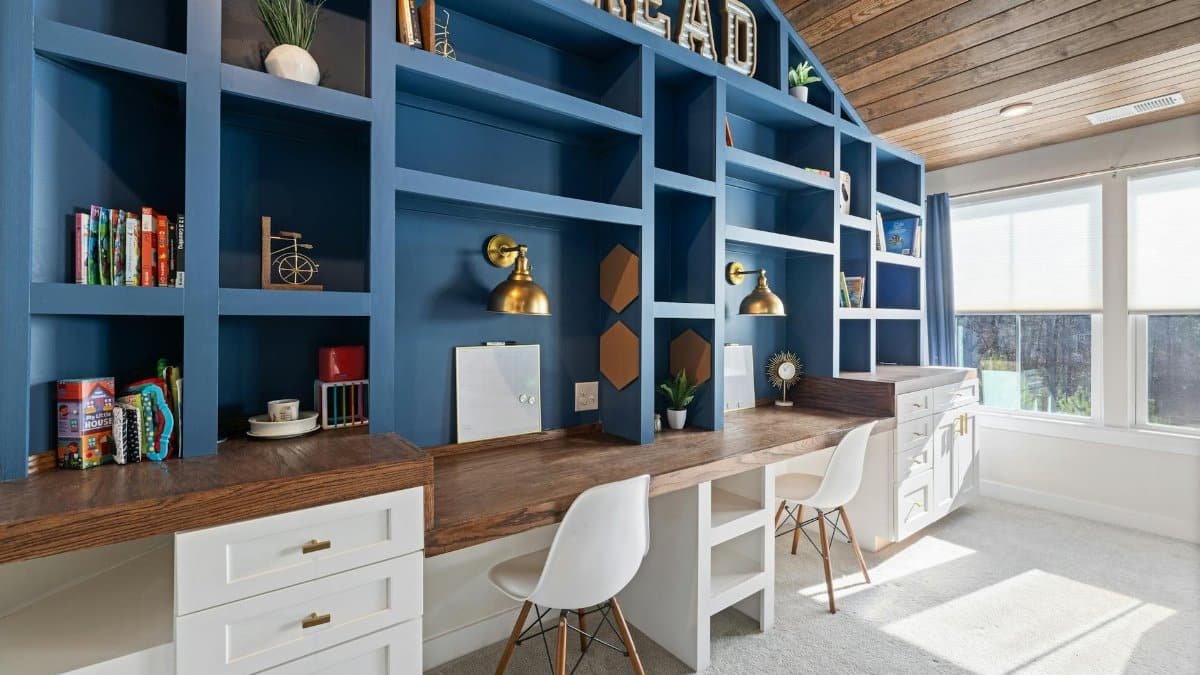 Bright home study room with custom blue bookshelves, wooden desk, and white chairs.