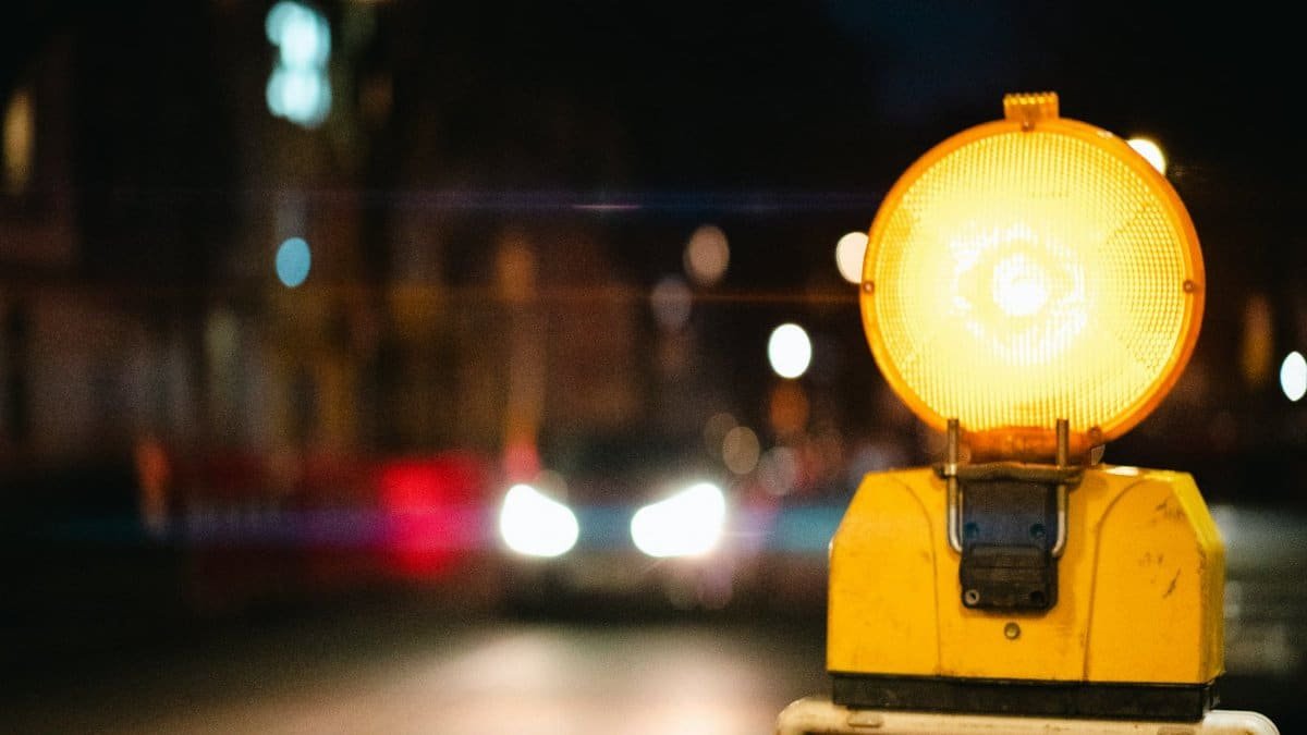 A night scene showing a bright yellow traffic warning light in an urban setting.