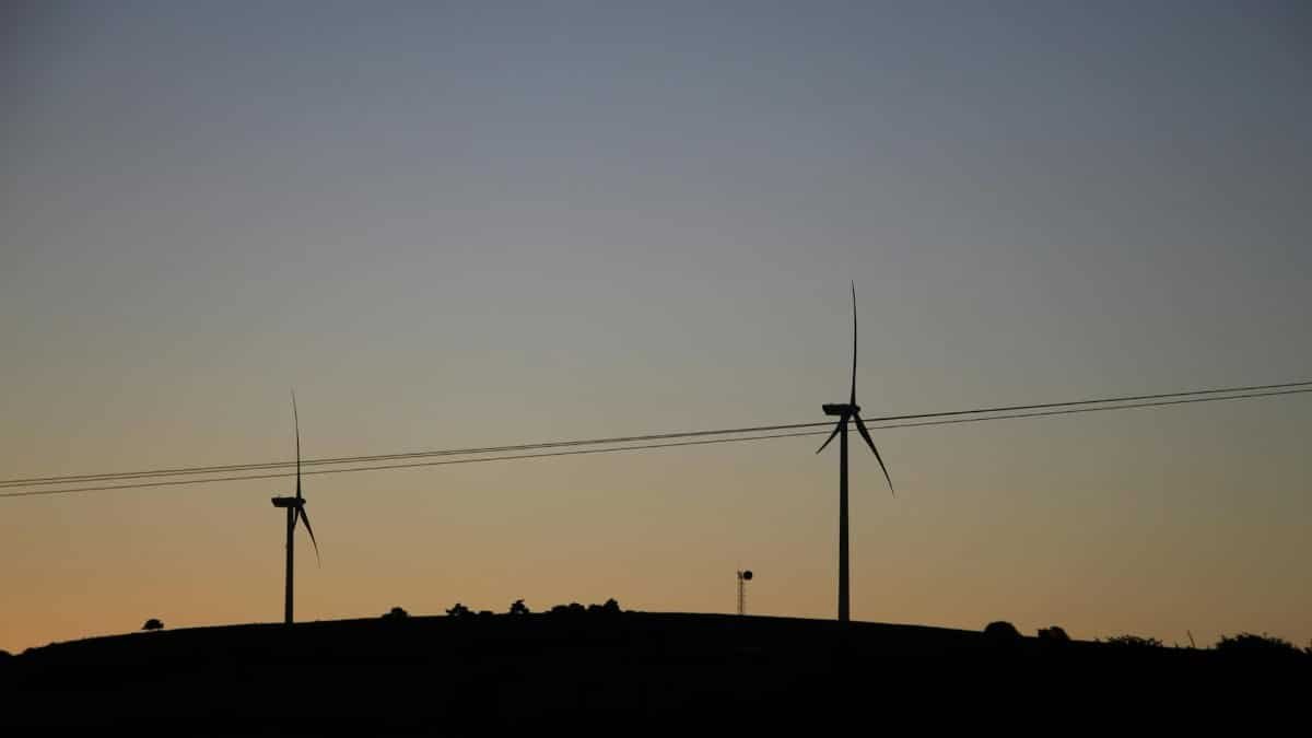 Silhouetted wind turbines at twilight symbolize sustainable energy against a sunset backdrop.