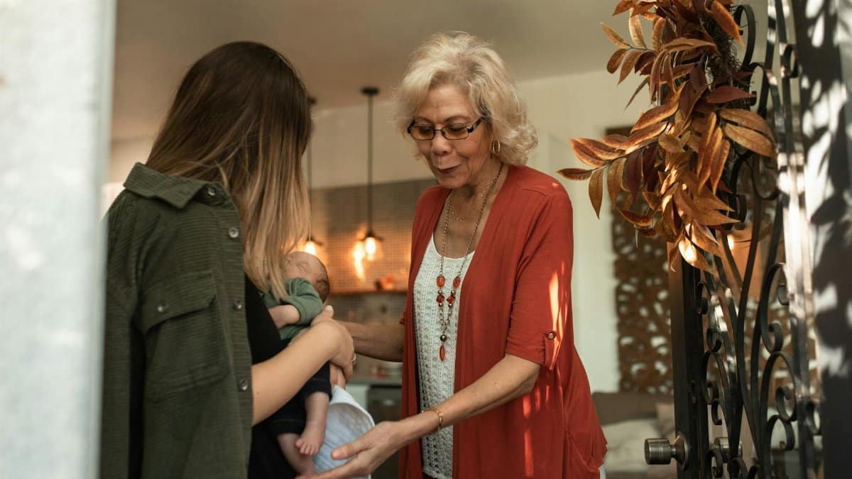 A tender moment of a grandmother greeting a family with a newborn baby during a holiday gathering.