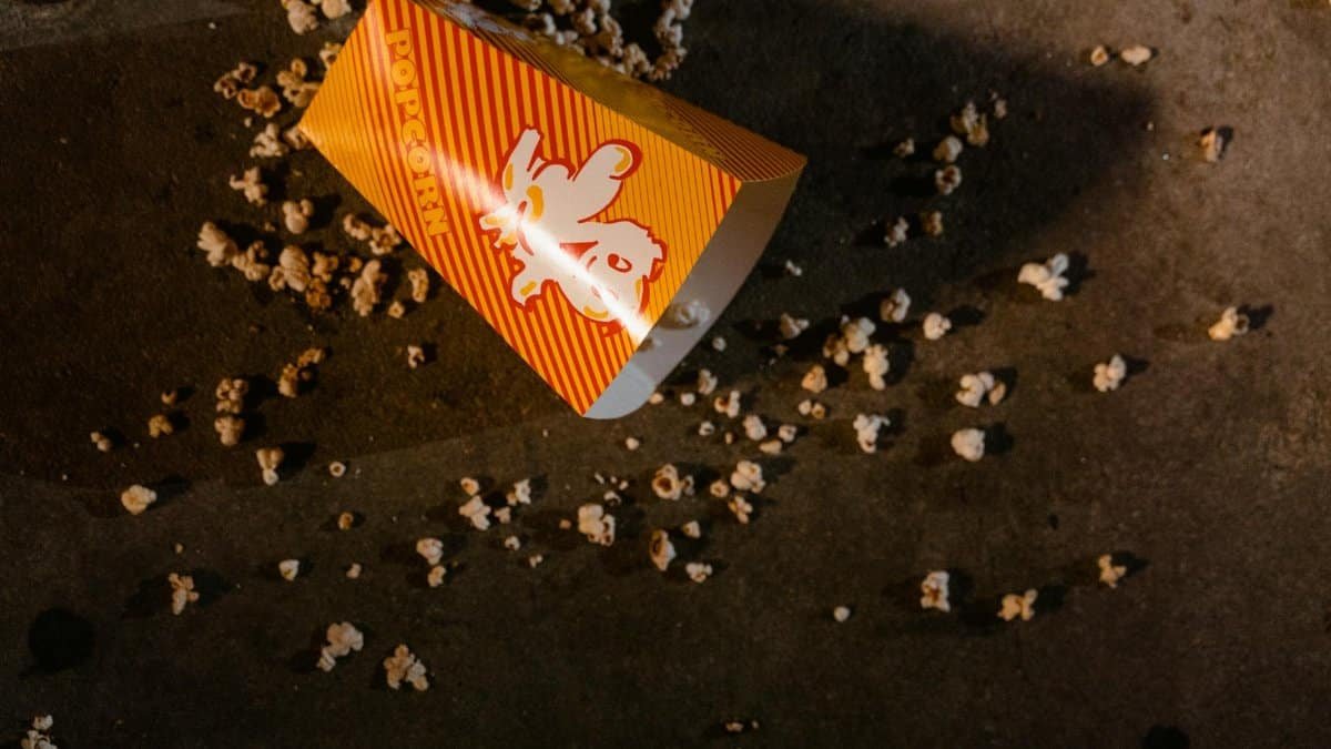 Closeup of a spilled popcorn container on a dark theater floor, creating a cinematic feel.