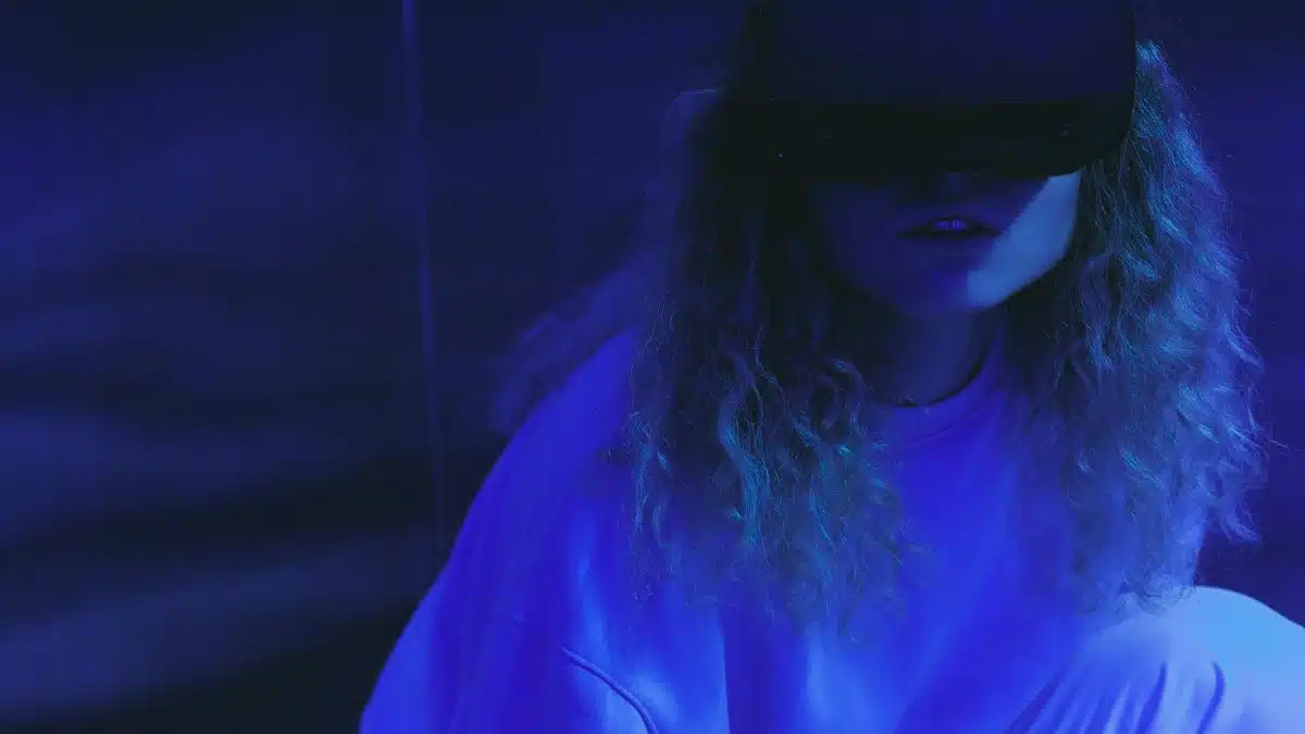 A woman wearing a VR headset enjoys a virtual reality experience in neon lighting.