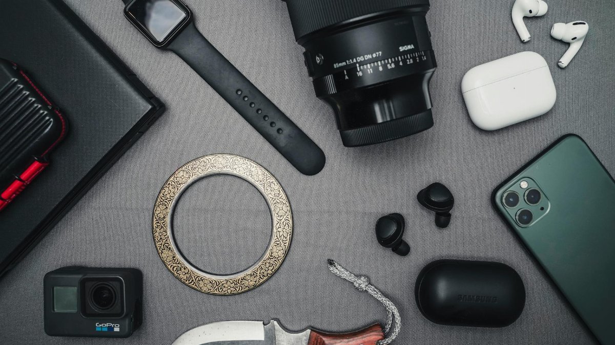 Flat lay of tech gadgets and personal accessories including camera and smartwatch.