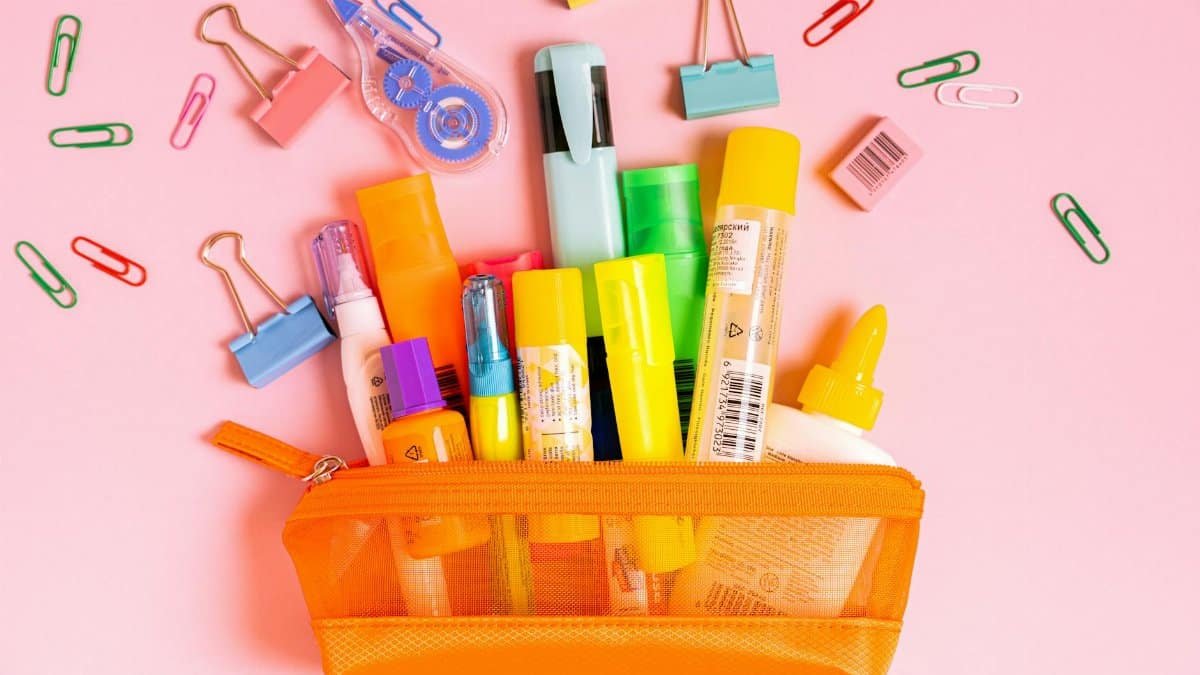 A vibrant collection of office supplies in an orange pouch against a pink background.
