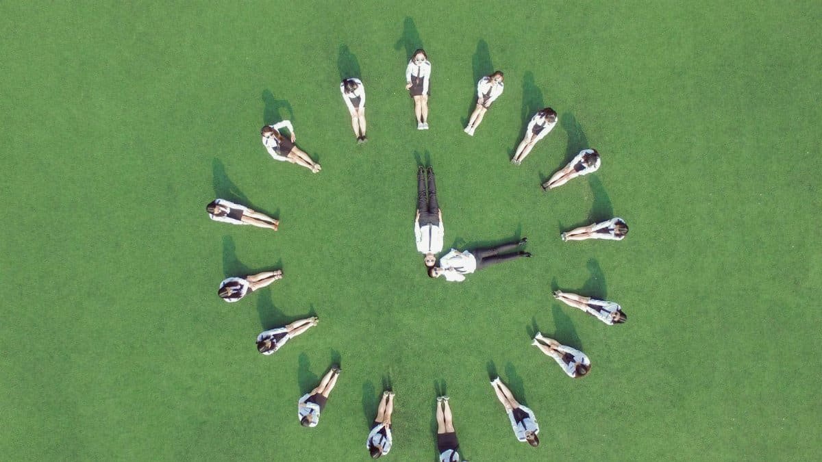 Aerial view of students forming a clock shape on a green field, symbolizing teamwork and time management.