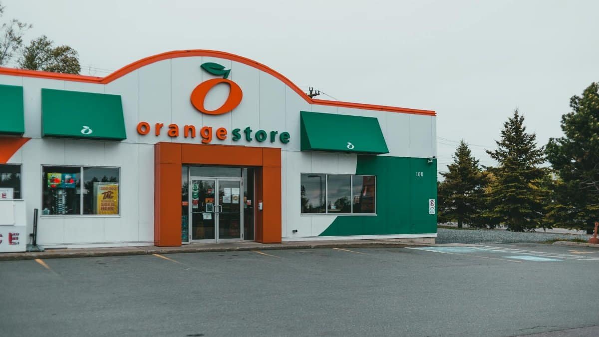 Exterior view of a modern orange store with an empty parking lot, displaying unique architecture.