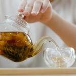 Adult woman pouring herbal tea into a cup, showcasing a cozy indoor tea ritual.