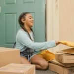 Young girl with braided hair sorting delivery packages on a porch.