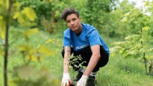 A dedicated volunteer planting a tree sapling in a lush green park environment.
