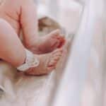 Close-up of newborn baby feet with hospital ID bracelet, symbolizing new beginnings.